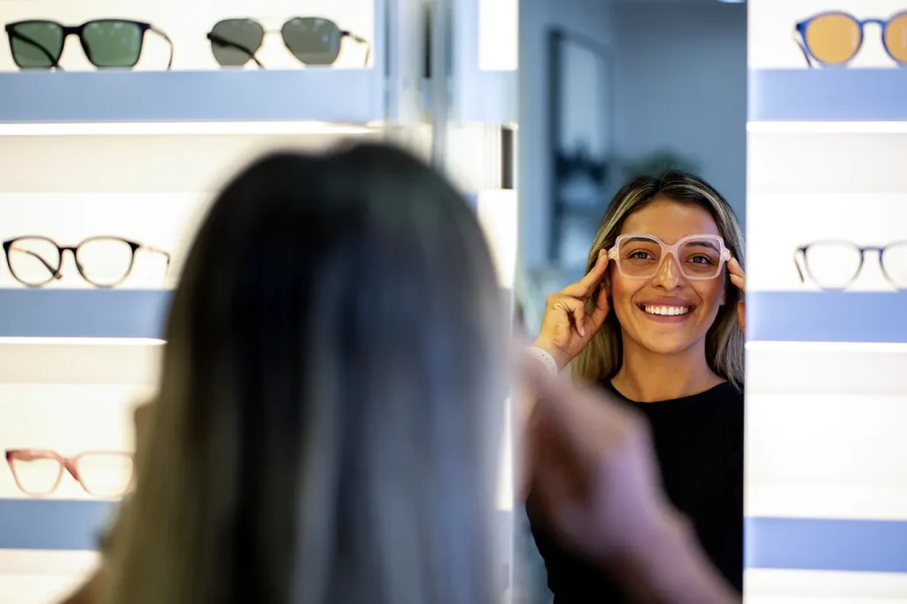 A woman trying out a new stylish pair of glasses in the clinic, looking at her reflection in the mirror